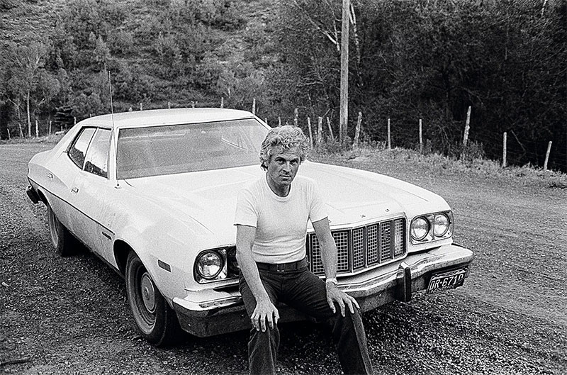 portrait du designer Pierre Paulin assis sur une voiture