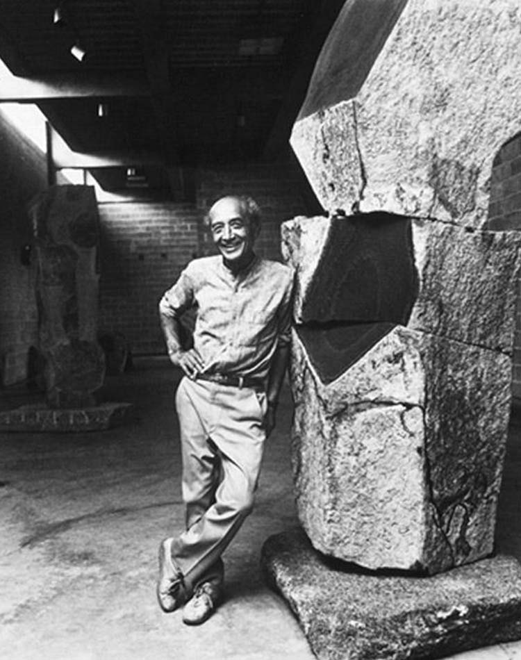 Isamu Noguchi posant à côté de son oeuvre